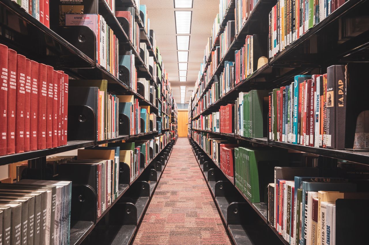Long corridor of library bookshelves showcasing diverse textbooks and literature.